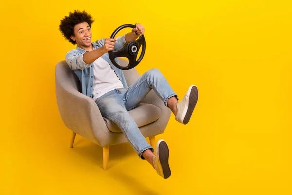 stock image Full size photo of overjoyed carefree person sit chair hands hold wheel empty space isolated on yellow color background.