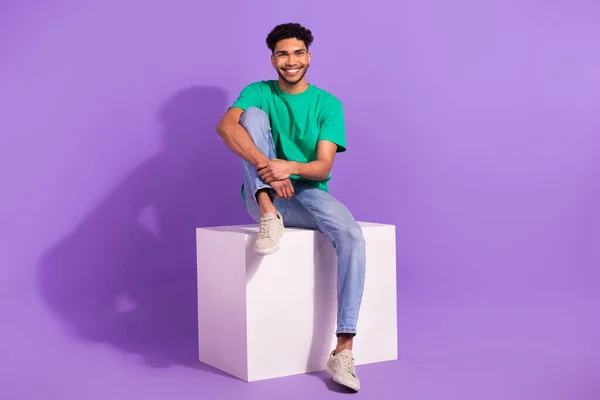フルボディサイズ写真の若い陽気な男座ってプラットフォーム良い気分待っている部屋を分離上の紫色の背景 — ストック写真