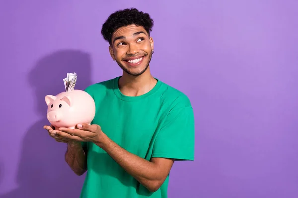 Photo of positive minded man hands hold money bank pig look empty space isolated on violet color background.