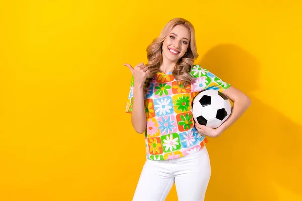 かわいい女性の写真は花のプリントTシャツ保持サッカーボール親指空のスペース孤立黄色の色の背景 — ストック写真