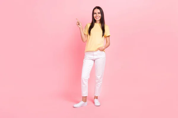 可愛いです女性の完全な長さ写真を身に着けている黄色Tシャツ指摘指空スペース隔離されたピンク色背景 — ストック写真
