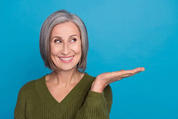 滑稽的退休女士举着敞开大门的棕榈广告的近照有趣的新奇产品穿套头衫孤立的蓝色背景 — 图库照片