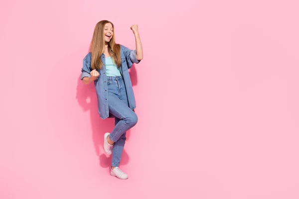 魅力的な若い十代の女性のフル長いです写真を上げる拳悲鳴Hooray着用トレンディーなジーンズ服ピンク色の背景に隔離 — ストック写真