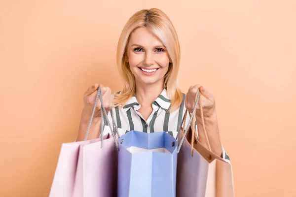 満足退職した女性の肖像ボブヘア縞のFormalwear示す新しい服でショッピングバッグに隔離されたベージュ色の背景 — ストック写真