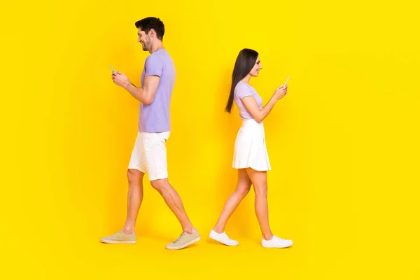 魅力的な女性の男性の電話の試合のフルサイズの写真バックバックは黄色の色の背景に隔離された流行の紫の外観を着用歩く — ストック写真