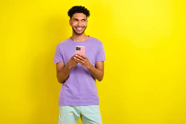 英俊潇洒的男人的画像拿着智能手机笑容满面 看上去空荡荡的 被黄色的背景隔开了 — 图库照片