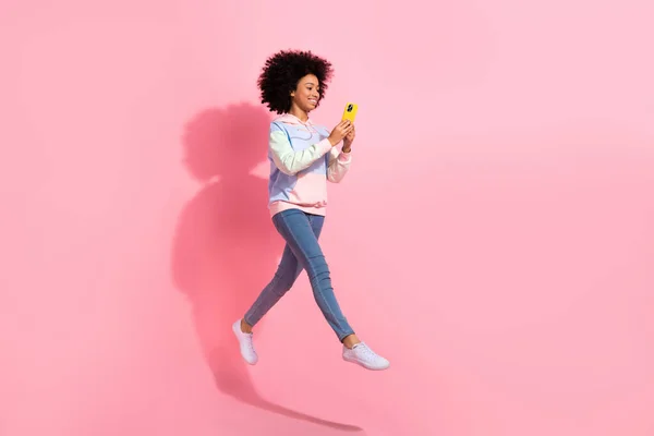 stock image Full length photo of pretty shiny small kid wear sweatshirt communicating modern device jumping isolated pink color background.