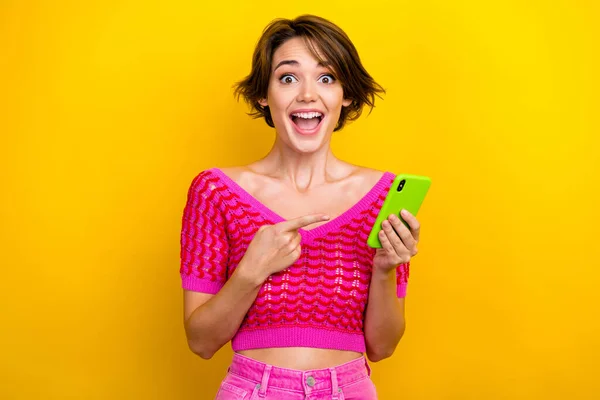 短い散髪と恍惚クレイジー面白い女性の肖像はピンクのニットトップ演出を身に着けていますスマートフォンで黄色の色の背景に孤立 — ストック写真