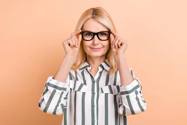 楽観的なフレンドリーな女性の肖像ストライプ形式の手はベージュの色の背景に隔離された視力検査で眼鏡に触れる — ストック写真