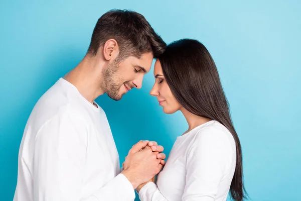2人の楽しい愛らしい楽観的なカップルの写真青の色の背景に隔離された手を携えて白いシャツを身に着けている — ストック写真