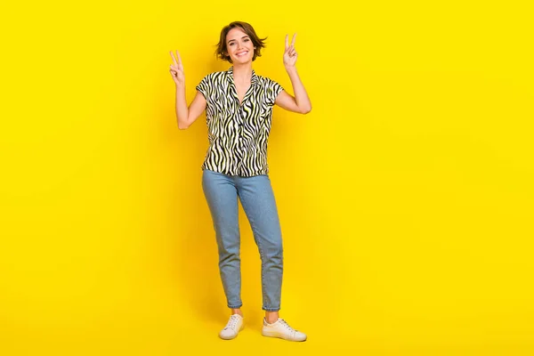 フルサイズの写真の面白い素敵な女性励起ショーVサインシンボル手着用プリントブラウスジーンズシューズ隔離された黄色の色背景 — ストック写真