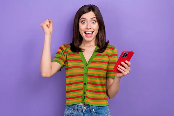 Portret Optymistycznej Dziewczyny Ubrany Paski Sweter Trzymać Smartfon Podnieść Pięść — Zdjęcie stockowe