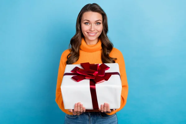 Photo of pretty excited lady dressed orange pullover holding big gift box isolated blue color background.