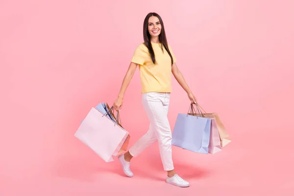 フル長さ写真のファンキーな光沢のある女性の服を着て黄色Tシャツ歩行保持買い物客隔離ピンク色の背景 — ストック写真