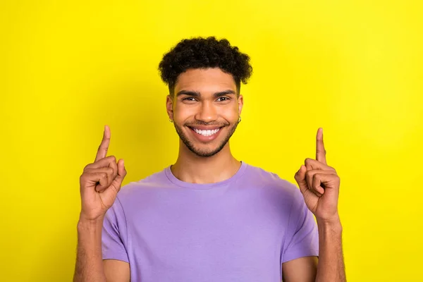 兴奋迷人的男人穿着紫色的T恤指着两个手指空空如也的黄色背景的照片 — 图库照片