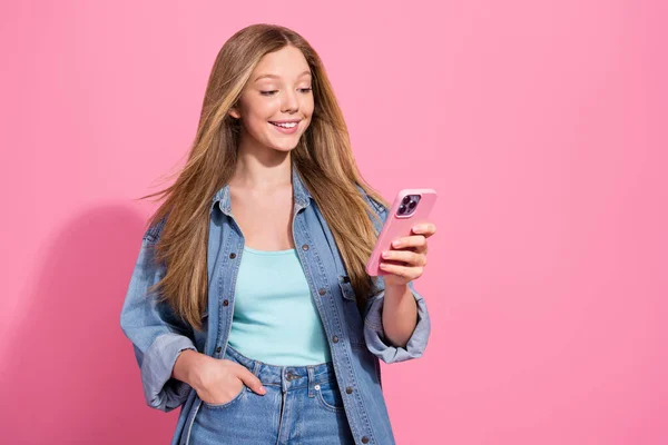 正の可愛い女の子の肖像画はスタイリッシュな衣装を着て書くInstagramのFacebookのポストスタンドピンク色の背景に隔離された空のスペース — ストック写真