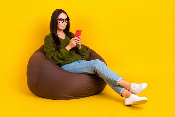 完全な長さ写真の甘いです可愛いです女性身に着けていますKaki Pullover座って豆袋タイピングTwitter空のスペース隔離された黄色の背景 — ストック写真