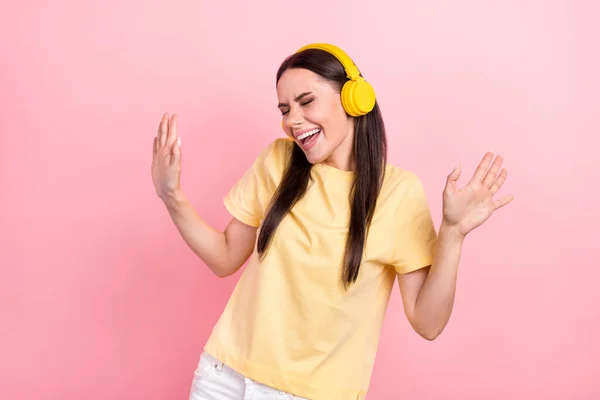 興奮した愛らしい女性の写真黄色のTシャツのヘッドフォンを身に着けている楽しいダンス隔離されたピンクの色の背景 — ストック写真