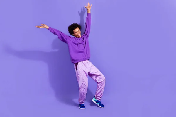 stock image Full length photo of pleasant funny guy dressed violet stylish sportswear sneakers raising arms up isolated on purple color background.