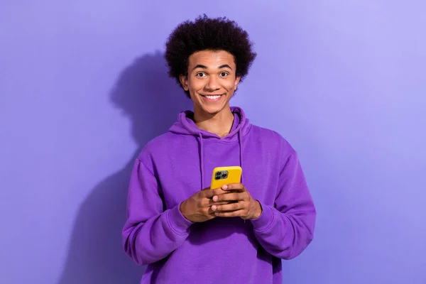 照片上的男人面带微笑 用智能手机聊天 用紫色背景隔离发短信 — 图库照片