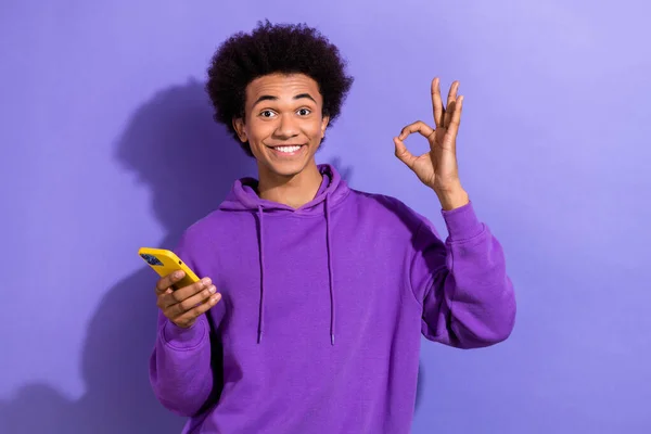 英俊潇洒的男人手持灵巧的手机手指头 在紫色背景下表现出独特的符号 — 图库照片