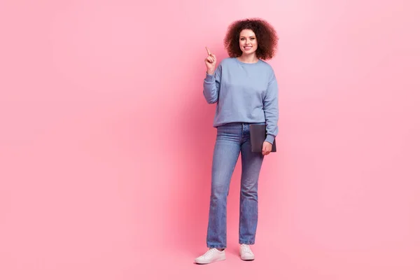 全身上下都是身穿蓝色运动衫牛仔裤的年轻女商人 她们把电脑直接手指空空的地方隔离在粉红色的背景下 — 图库照片