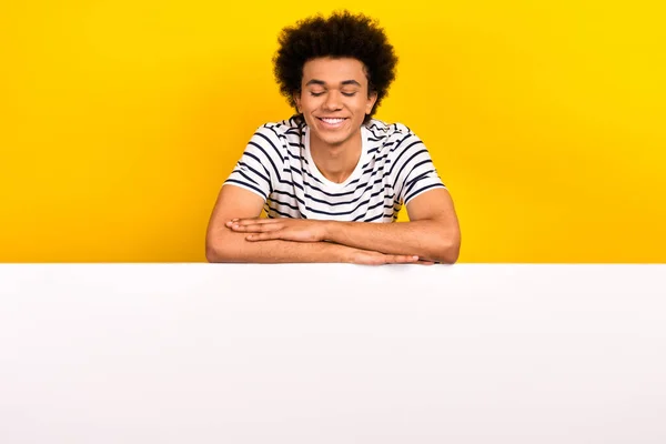 若い満足マーケティング担当者の写真黄色の色の背景に隔離されたブランドの広告を楽しむ紙のバナー上にストライプのTシャツ折り手 — ストック写真