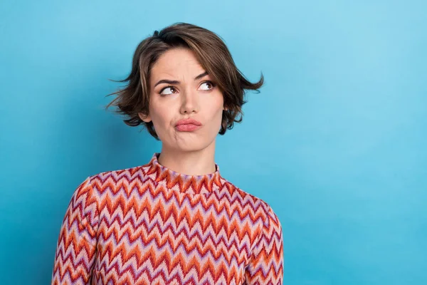 Photo of pretty serious lady looking side empty space suspicious person wear print shirt isolated blue color background.