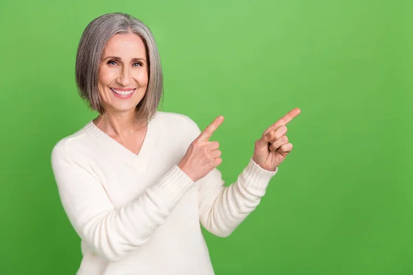 迷人的老太太直接手指新奇空旷的空间广告横幅身穿白色时髦衬衫孤零零的绿色背景的照片 — 图库照片