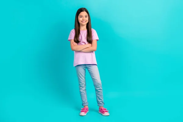 全身上下的幼女干部抱臂微笑着穿斜纹棉布牛仔裤粉色T恤衫运动鞋 以青色背景隔离 — 图库照片