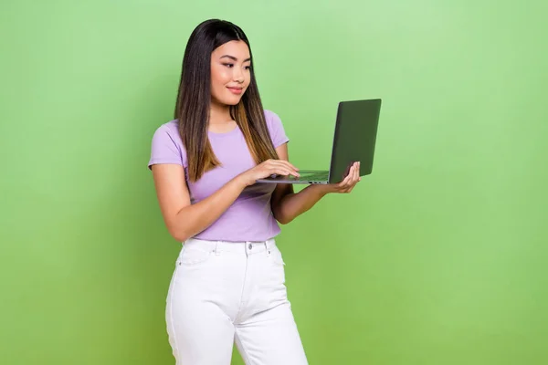 照片上 年轻的韩国女士身穿紫色T恤 手持上网本代码程序员在绿色背景下推出网站 — 图库照片