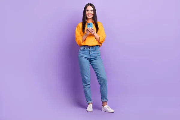 楽観的な豪華な女性のフルサイズの写真ストレートヘアドアオーバーサイズシャツホールドスマートフォン読み取りポスト隔離された上に紫色の背景 — ストック写真