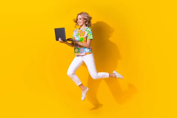 全长照片 甜美兴奋的女人穿着花纹T恤衫阅读邮件现代装置跳跃孤立的黄色背景 — 图库照片