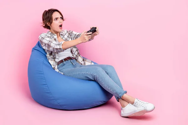 stock image Full length photo of impressed person sit bag hold controller play video games stare empty space isolated on pink color background.