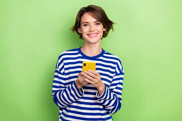 若い楽観的な女性のブログの写真は 緑の色の背景に隔離されたアップルのIphoneのブラウジングショッピングストアの購入広告を保持します — ストック写真