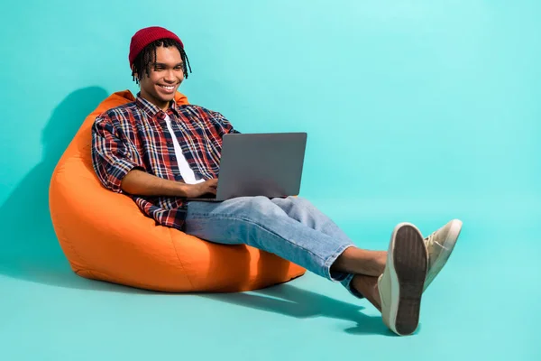 身着格子衬衫牛仔裤的聪明人坐在手提电脑上的邮袋上 用单色背景隔绝的电子邮件打字 — 图库照片