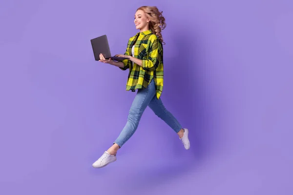 甜美兴奋的女士穿着格子花黄衬衫跳上高效能现代小玩意孤立的紫罗兰背景的全长照片 — 图库照片