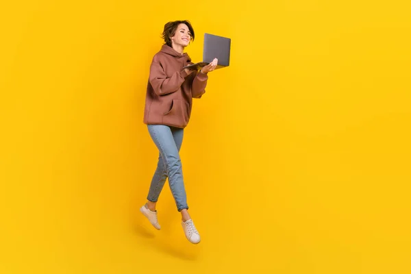 아가씨 점프의 초상화노란 배경에 넷북빈 공간을 — 스톡 사진