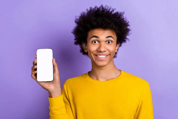 黄色衬衫的照片年轻人笑着拿着智能手机三声接口触摸屏灵敏度测试隔离紫色背景 — 图库照片