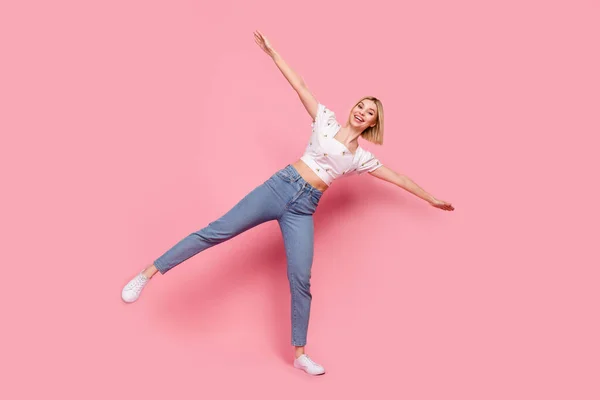 フルサイズ写真の面白い若い女の子夏のパーティースタイリッシュな服を着た白いトップデニムジーンズホールドバランス絶縁ピンク色の背景 — ストック写真