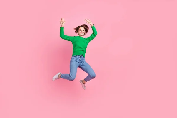 全长照片 兴奋快乐的女孩穿着绿色毛衣跳过空旷的空间孤立的粉红色背景 — 图库照片