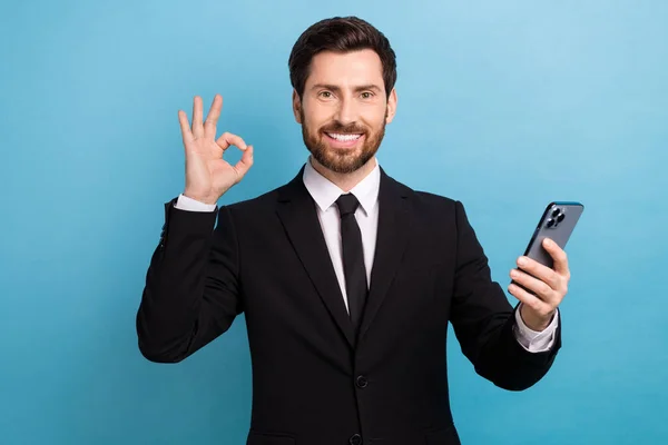 图为年轻成功的地产代理卖家在蓝色背景下手握手机的照片 — 图库照片
