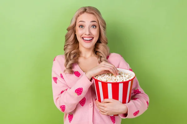 驚きの若い女の子の写真ブロンド波の髪の摩耗イチゴシャツ笑いホールドポップコーン食べる楽しみショーで隔離された緑の色の背景 — ストック写真