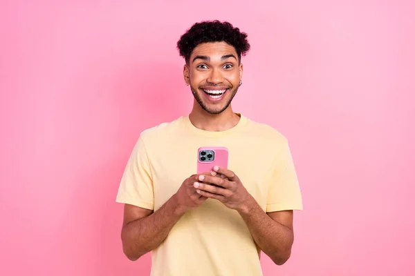 一个喜形于色 头戴非洲发耳环的男人拿着智能手机的画像 在粉色背景下阅读有趣的文章 — 图库照片
