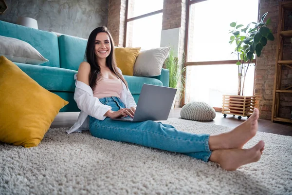 Photo of positive smart lady marketer sit carpet in shiny living room using netbook communicating in social media.