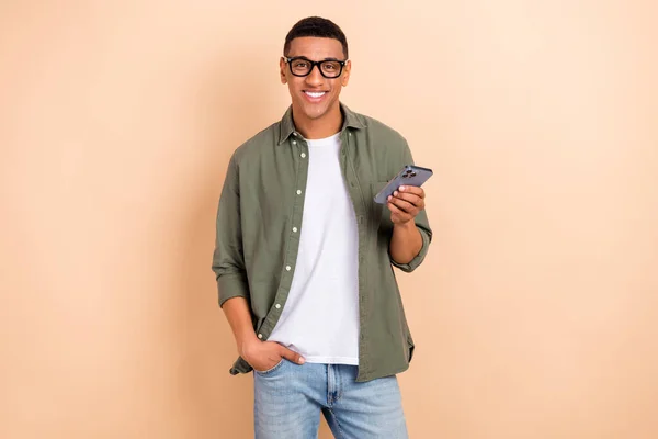 stock image Photo of cheerful attractive young man toothy smile hold apple iphone gadget isolated on beige color background.