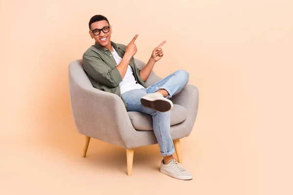 正代理人男人坐在舒适椅子上的全尺寸肖像显示手指空旷 用米色背景隔开 — 图库照片