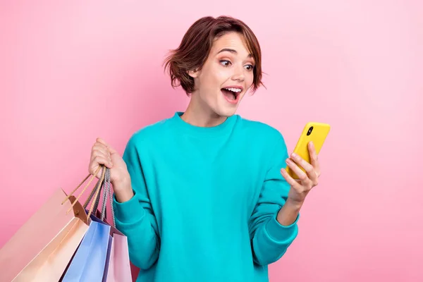 驚くべき陽気な女性の肖像は トレンディーなプルオーバーホールド電話を着用オンラインピンクの色の背景に孤立注文服を選択 — ストック写真