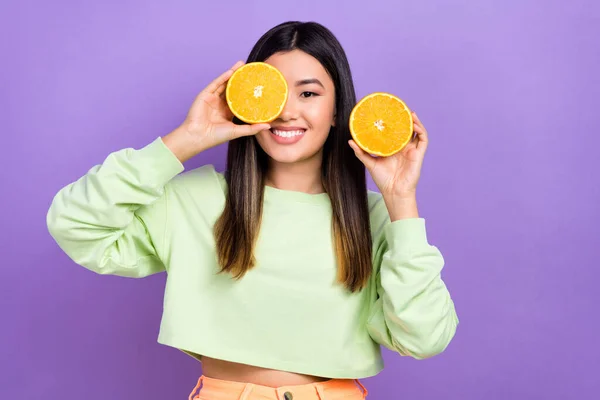 ストレートのヘアドアを持つ優しいかわいい女の子の肖像画は 紫色の背景に隔離された目にスタイリッシュなプルオーバーオレンジ果実を身に着けています — ストック写真
