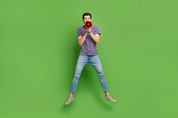 印象的なクールな男のフル長さの写真縞模様のTシャツジャンプ高叫び負荷スピーカー隔離された緑の色の背景 — ストック写真